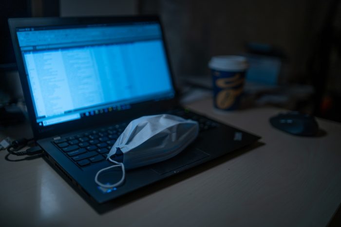 laptop in darkened room with surgical mask on the keyboard