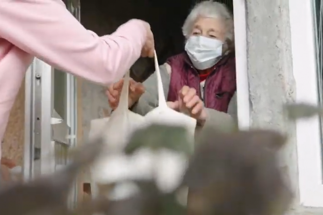 elderly woman in doorway reaches out for a food delivery