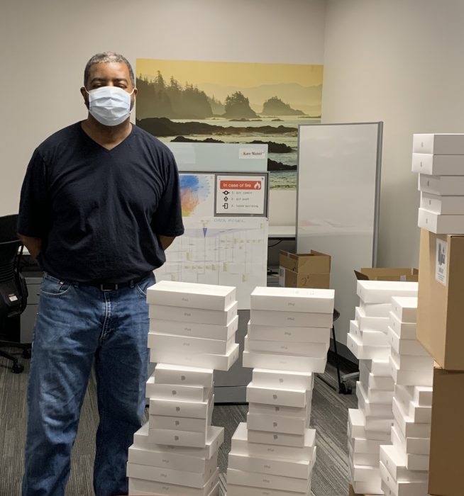 A School of Dentistry staffer stands next to piles of iPads. 