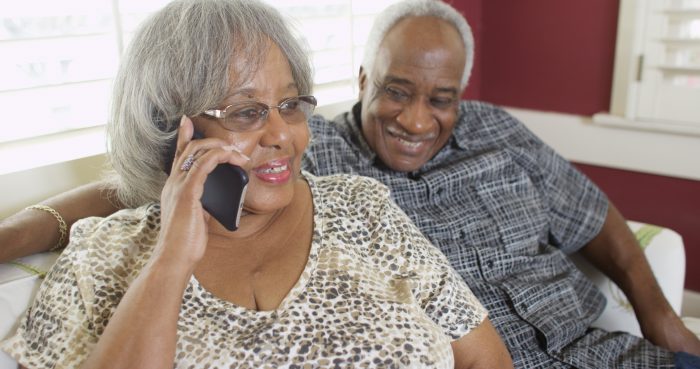 Two senior adults, one of them is on the phone.