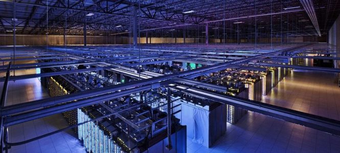 (Photo of a very large, dark room filled with glowing computers.)