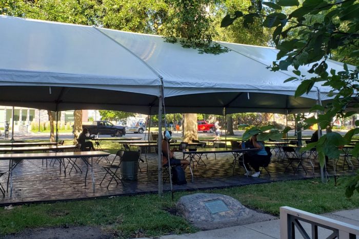 Large outdoor canopy with people seated at tables working on laptops