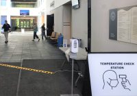 Hallway at UM-Dearborn with temperature check station in the foreground and people in the background