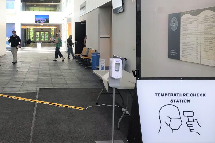 Hallway at UM-Dearborn with temperature check station in the foreground and people in the background