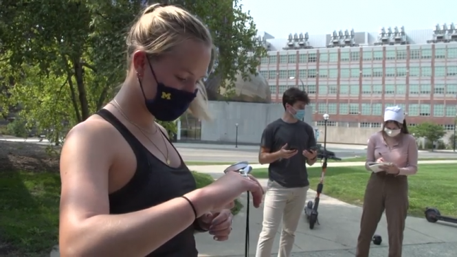 Female athlete wearing mask measuring blood oxygen. Two researchers in BG.