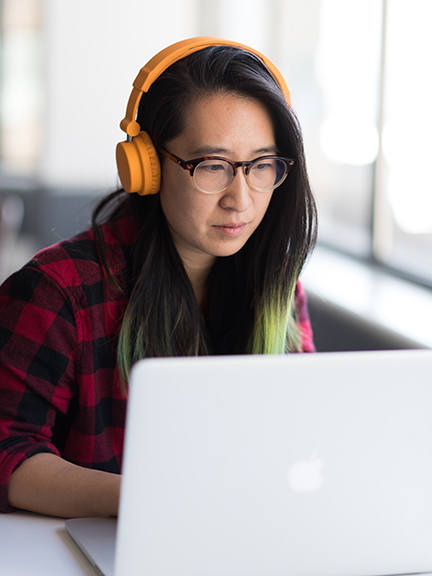 student with headphones at a laptop computer