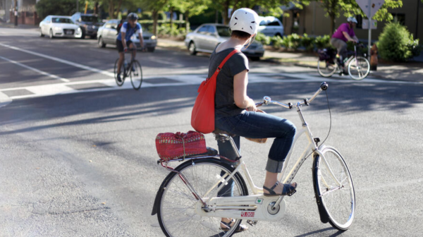 A bicyclist pauses at an intersection to let another bicyclist pass by. 
