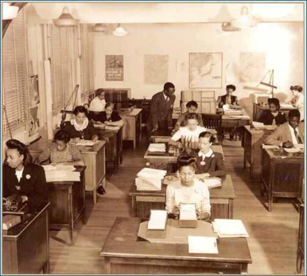 William Coffee is shown standing and consulting with a seated cryptologist.