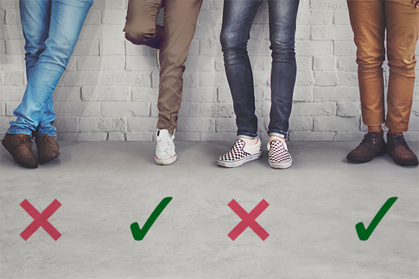 The lower half of four people standing side by side, wearing
medium blue jeans, khakis, dark blue jeans, and brown slacks; the
first and third are above red X's and the second and fourth are
above green checkmarks