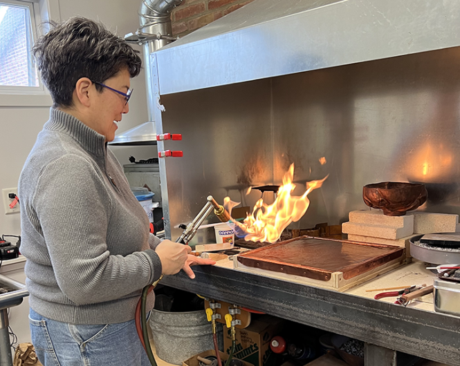 Amy Yamasaki is shown from a side profile with a blowtorch in her hand.