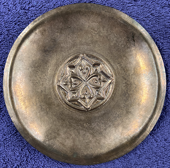 A shallow copper bowl with a small design in the center.