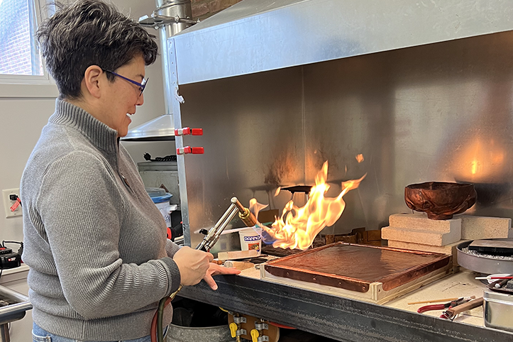 Amy Yamasaki is shown from a side profile with a blowtorch in her hand.