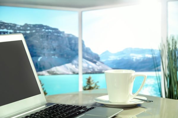 Laptop and coffe cup on a table with a lake-side view