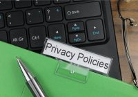 A file folder with a label that reads "privacy policies" is laying on top of a black computer keyboard.