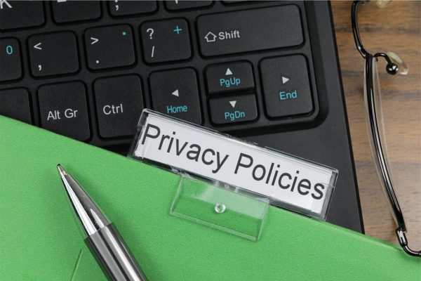 A file folder with a label that reads "privacy policies" is laying on top of a black computer keyboard.