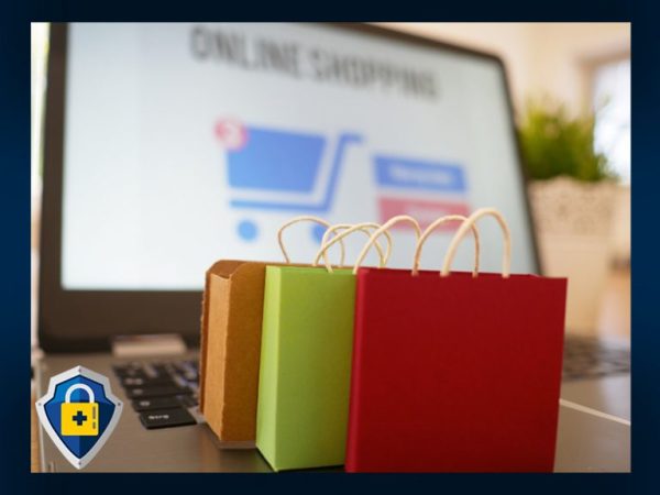 Three small gift bags sitting on a laptop with the laptop's monitor visible but blurry. The monitor appears to show online shopping. 