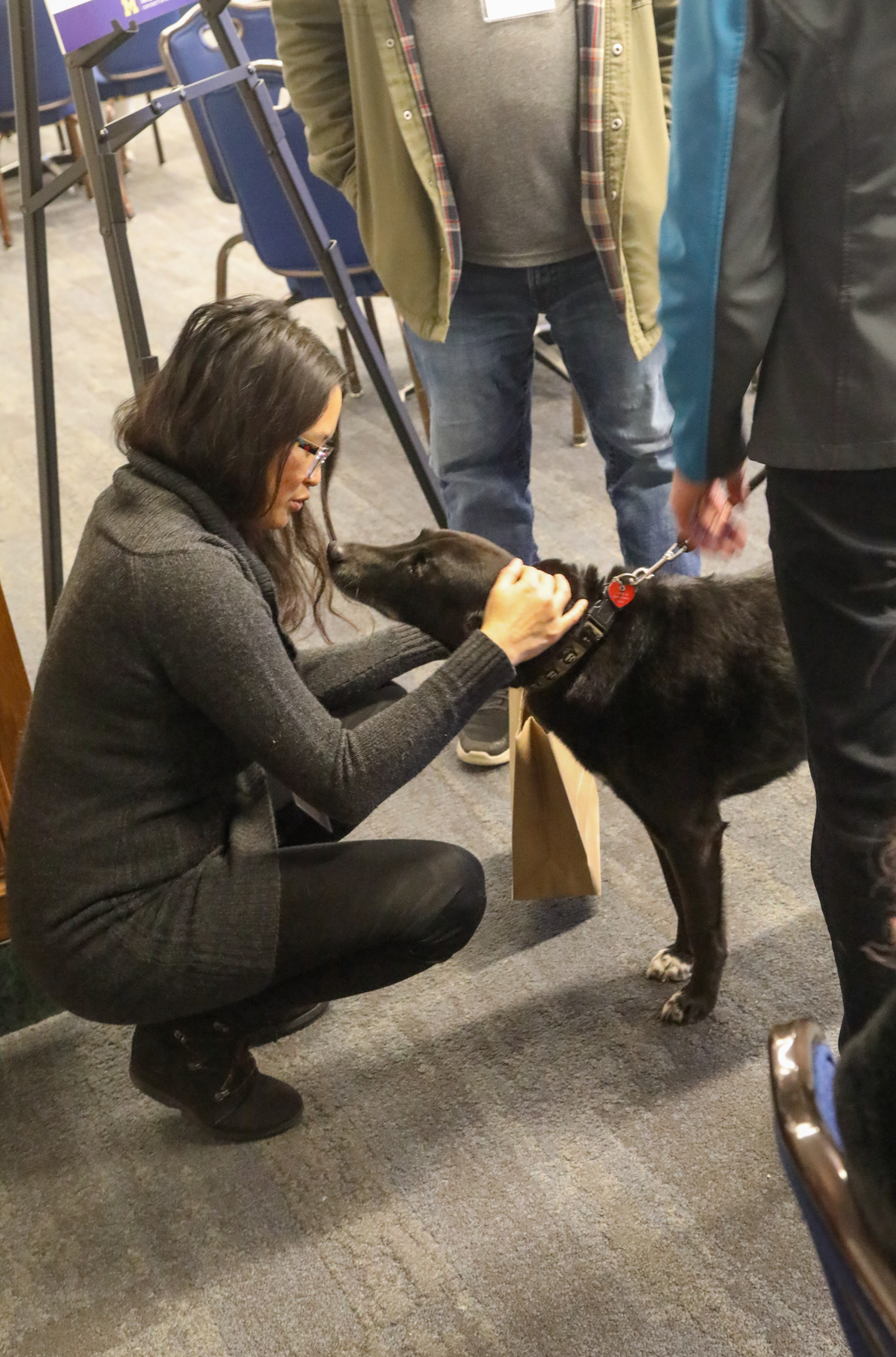 Women kneels down to pet a dog brought to the Tech Showcase and Social by Therapaws of Michigan.