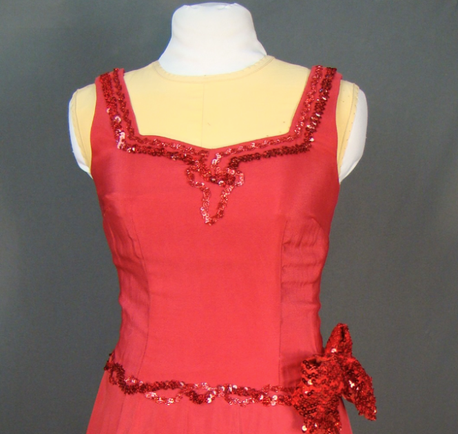 A red sleeveless dress with sequin detailing around the neckline and waist.