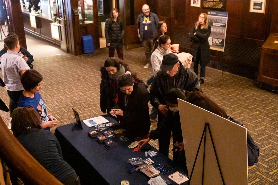 A group of people selecting various privacy at Michigan stickers during the 1984 40th-anniversary event at Michigan Theater.
