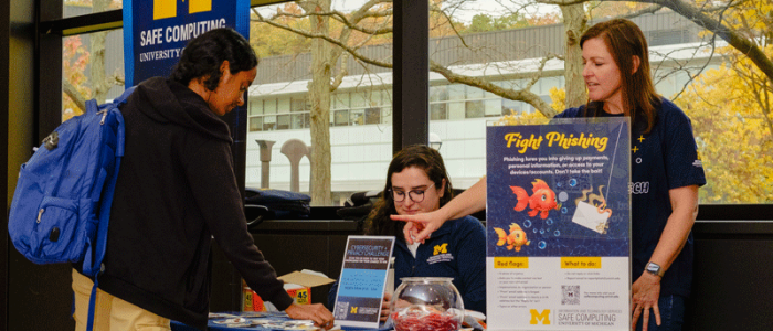 A student picks up pamphlets from an IA table at the Duderstadt Center