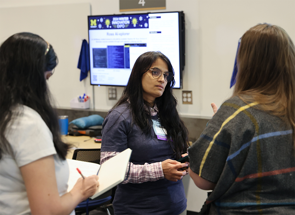 Three women having a discussion at the 2024 Winter Innovation Expo digital poster session.