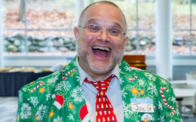 Joe Gregoria grinning at the camera in a Christmas-themed suit.