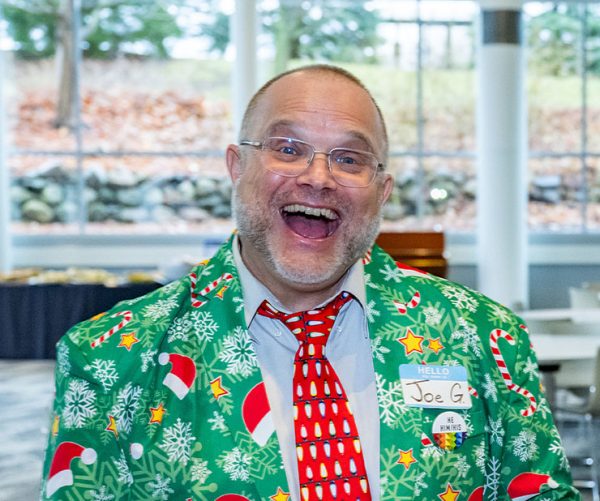 Joe Gregoria grinning at the camera in a Christmas-themed suit.