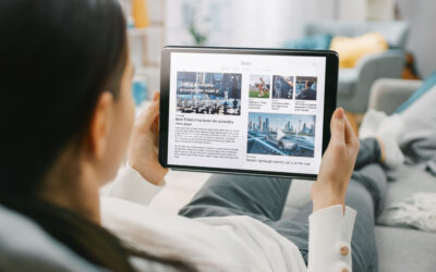 Over the Shoulder Shot of a Young Woman at Home Lying on a Couch and Using Tablet Computer in Horizontal Landscape Mode for Reading News about Technology.