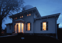 The U-M Detroit Observatory at night, lit in a warm glow from within.