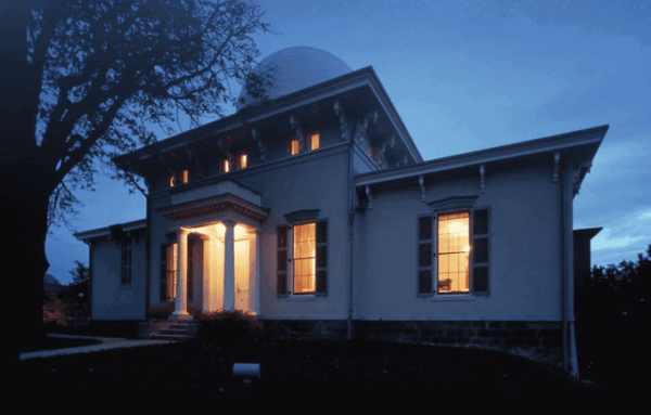 The U-M Detroit Observatory at night, lit in a warm glow from within.