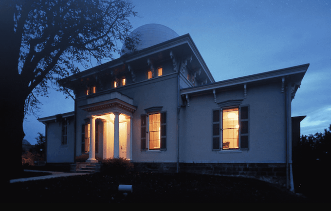 The U-M Detroit Observatory at night, lit in a warm glow from within.