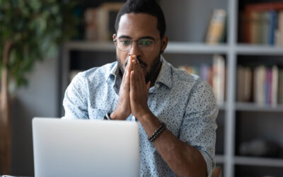 Shocked african business man looking at laptop feeling scared and frustrated about an unexpected online problem