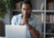 Shocked african business man looking at laptop feeling scared and frustrated about an unexpected online problem