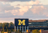 Big fluffy clouds hover over the Michigan Stadium Scoreboard.