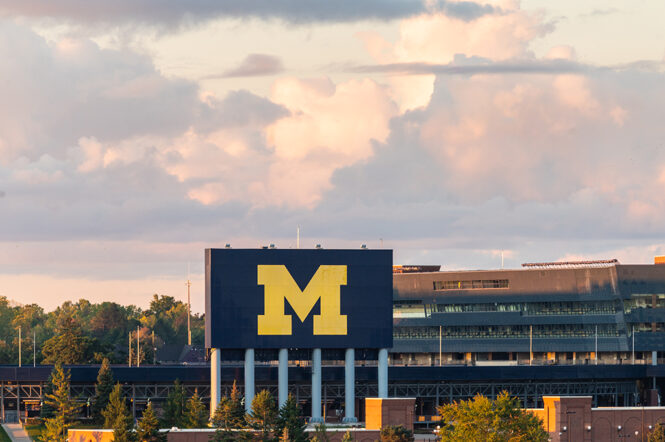 Big fluffy clouds hover over the Michigan Stadium Scoreboard.