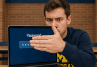 A U-M student looking concerned covers his password with his hand on his laptop.