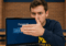 A U-M student looking concerned covers his password with his hand on his laptop.