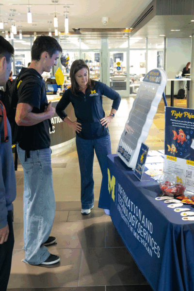 ITS Information Assurance staff member moderating a Plinko game at a Safe Computing pop up table.