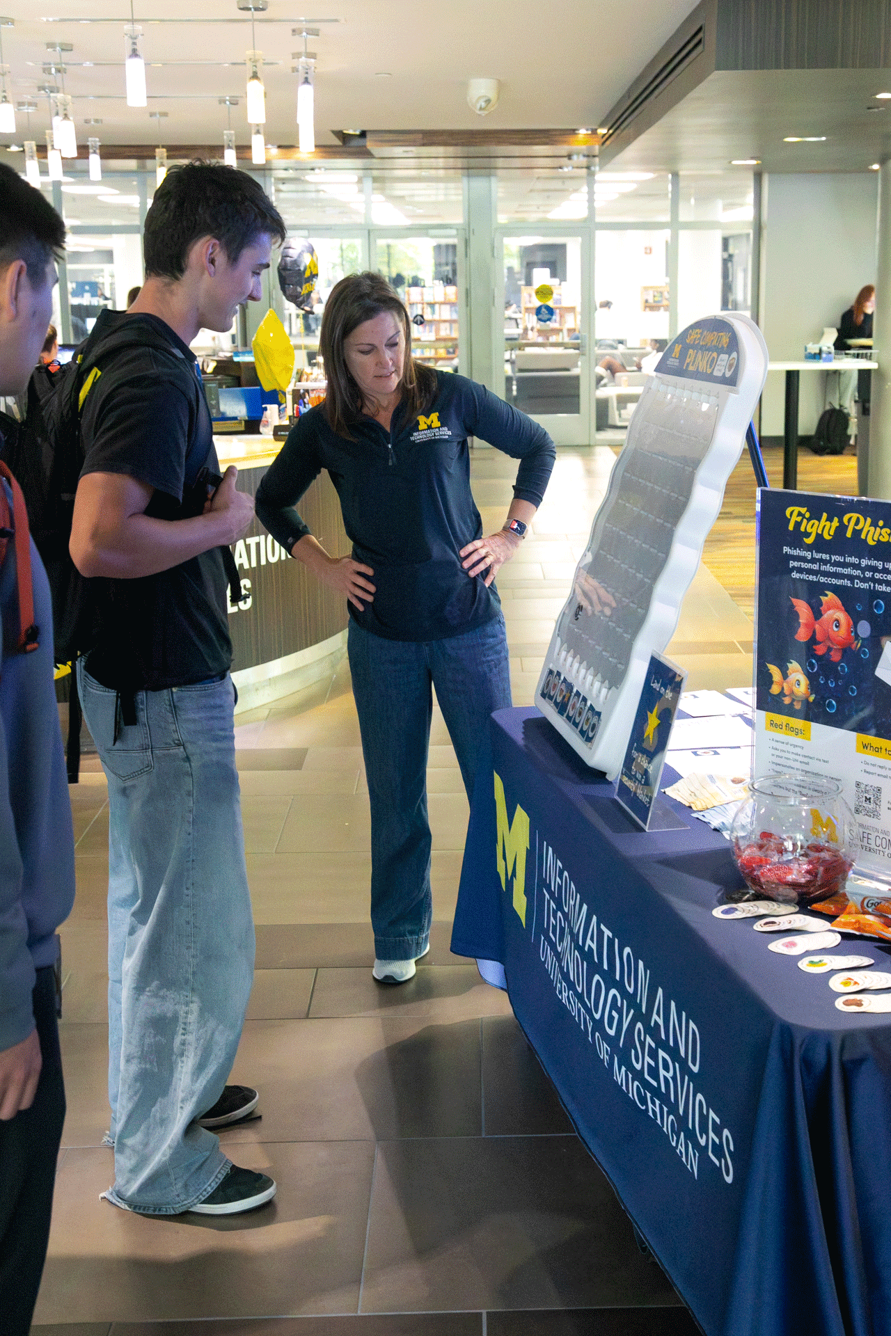 ITS Information Assurance staff member moderating a Plinko game at a Safe Computing pop up table.