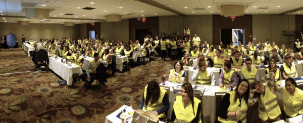 A conference room filled with college interns in safety vests.