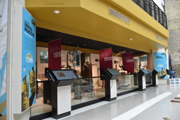 Atrium of museum with kiosks in front of dentistry artifact displays.
