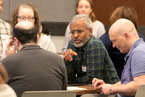 AI Summit attendees engaged in table-group discussions about various AI topics of interest