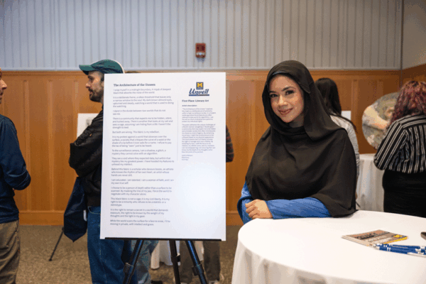 Sukria Malique standing with her poem, "The Architecture of the Unseen"