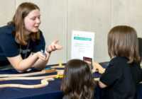 Future scientists listen to an adult explain a task.