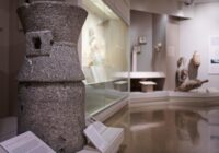 A vase sits in the foreground in front of other historical objects.