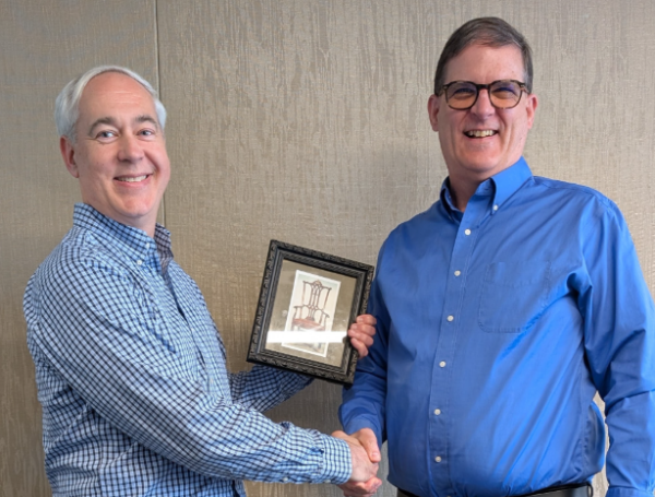 Ted Hanss is the new STAC chair. Outgoing chair, Marcus Bough, hands him an image of a regally-styled chair to signify change in leadership.